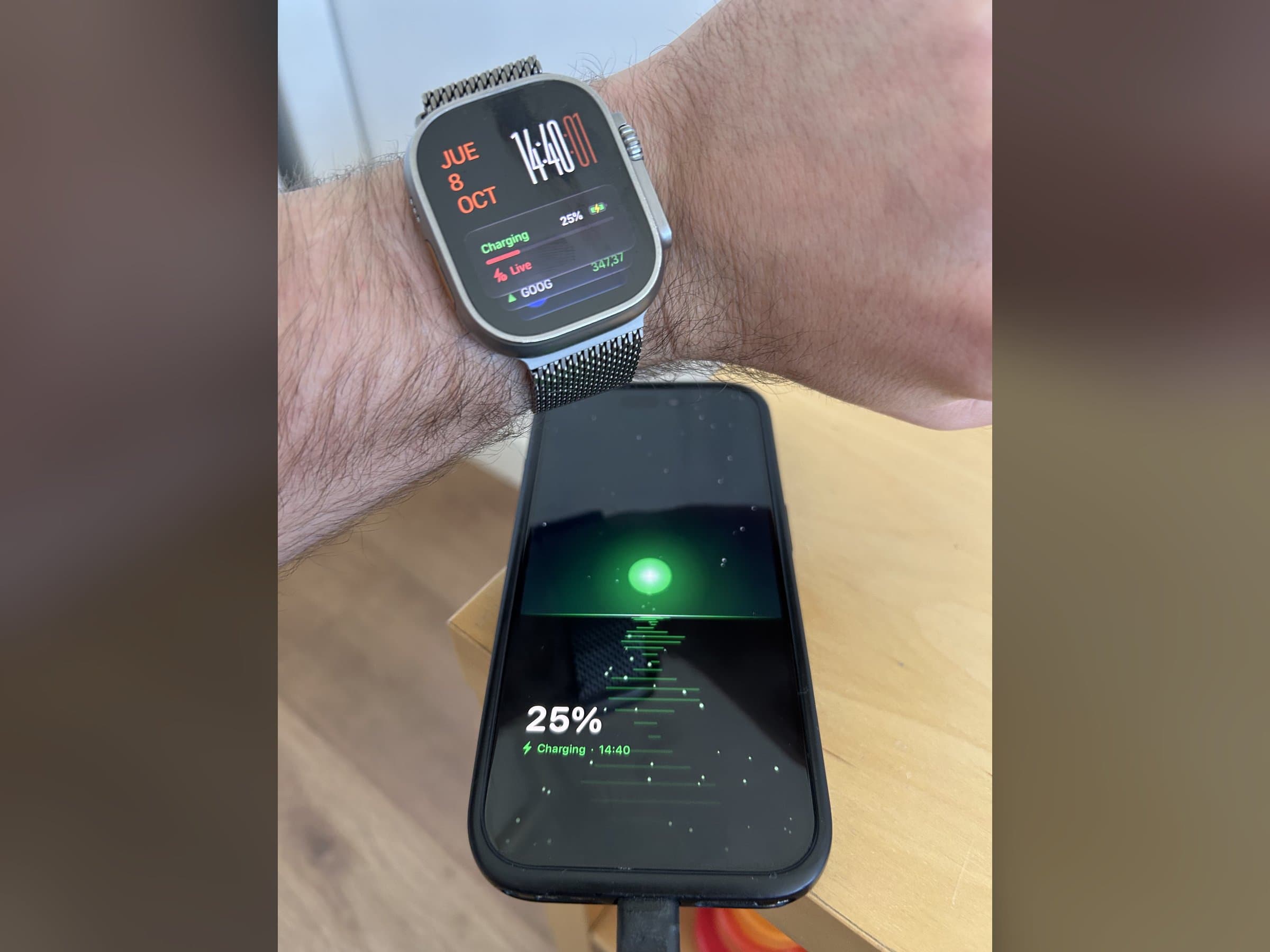 The phone charging with the charging animation at 25%, and the Charging Live Activity on an Apple Watch Ultra right above it